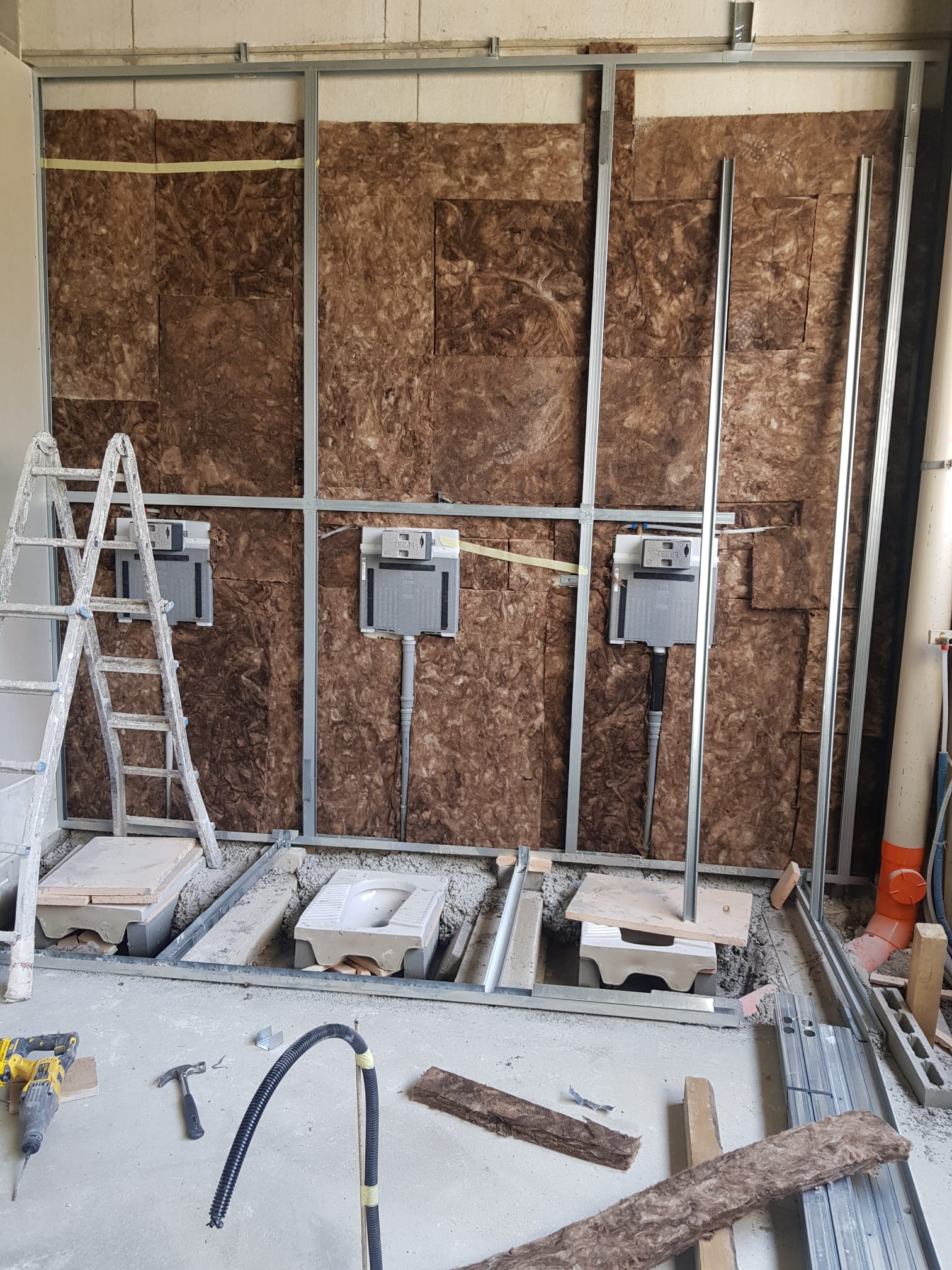Profili verticali davanti alla muratura esistente, con scala e materiali di cantiere.
