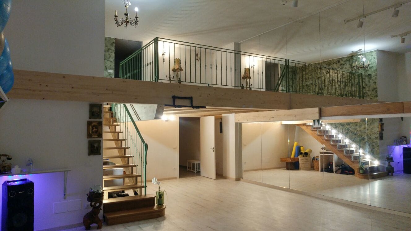 Soppalco con parapetto, scala e illuminazione nella parte inferiore dell’ambiente.