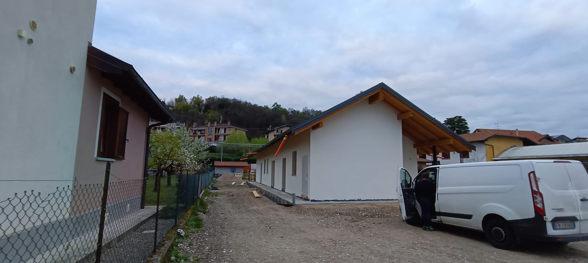 Facciata laterale chiara, copertura a falde e area esterna della casa.